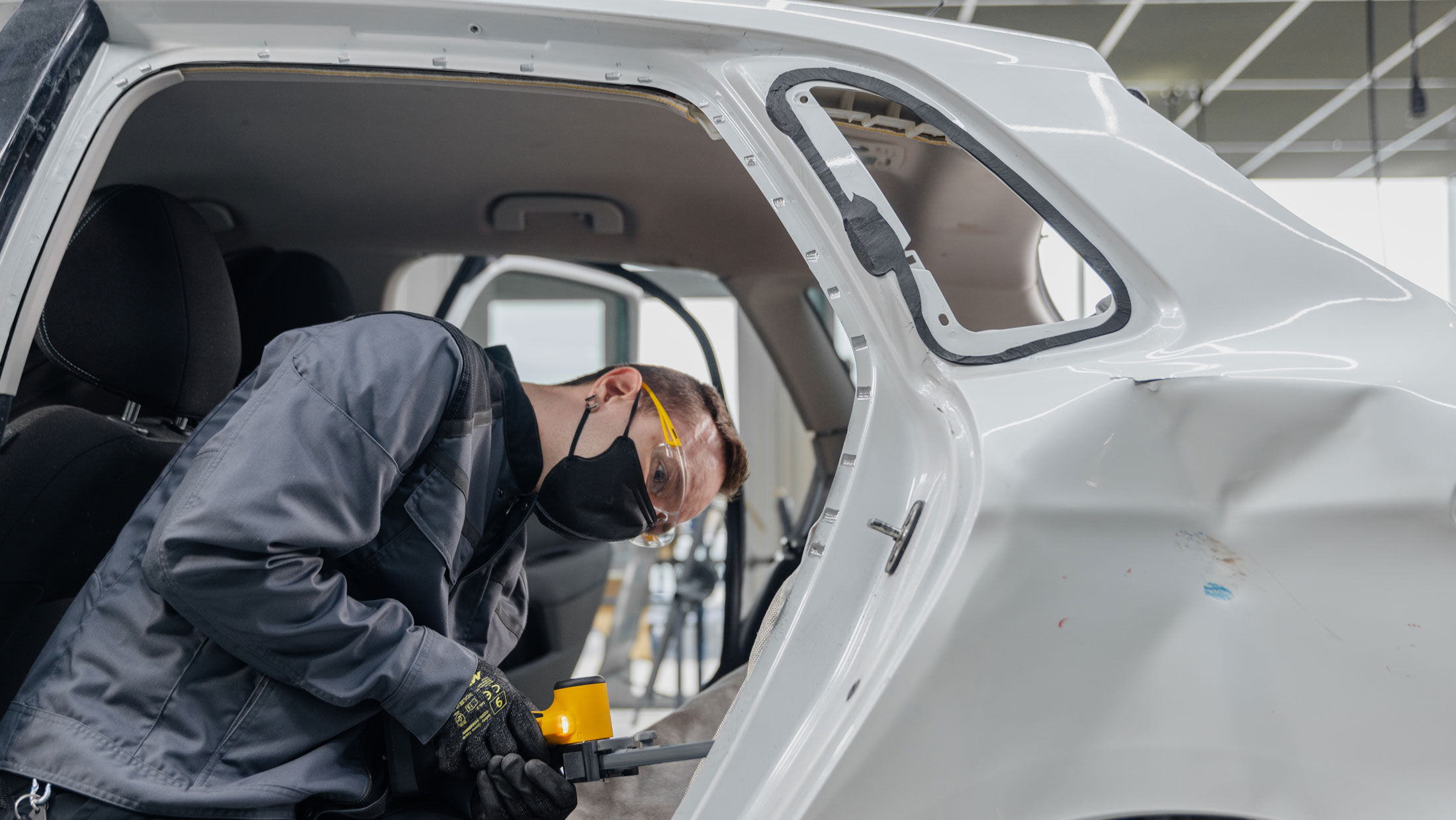 Mężczyzna używa szlifierki taśmowej Mirka przy samochodzie.