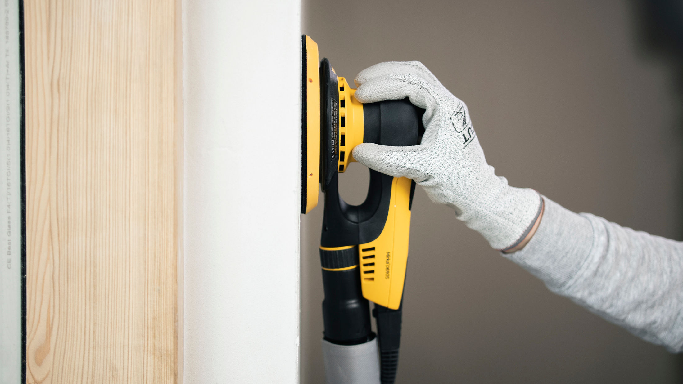 Mirka DEROS II electric sander sanding a drywall