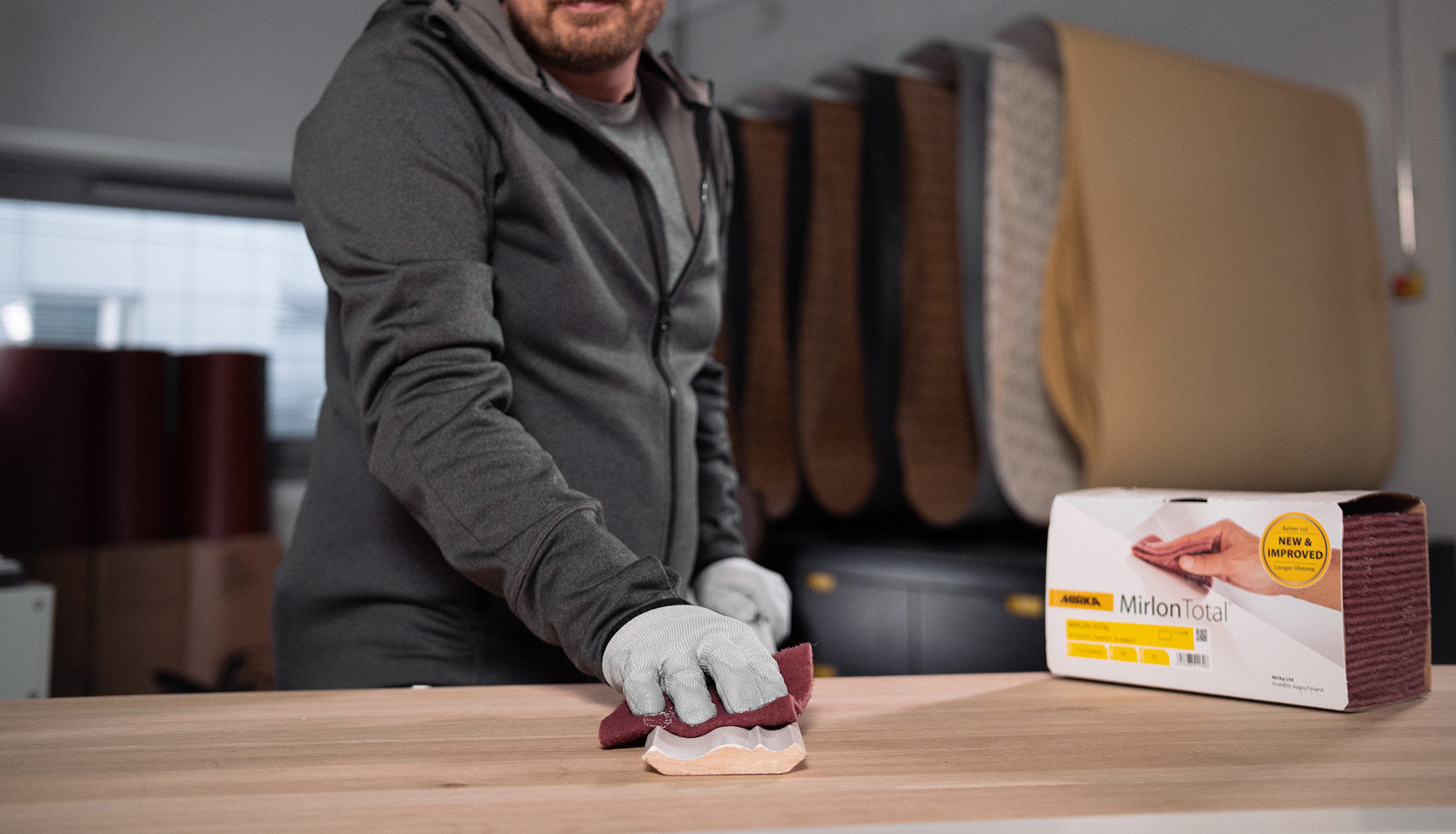 Man hand sanding profiles using Mirka Mirlon abrasive.