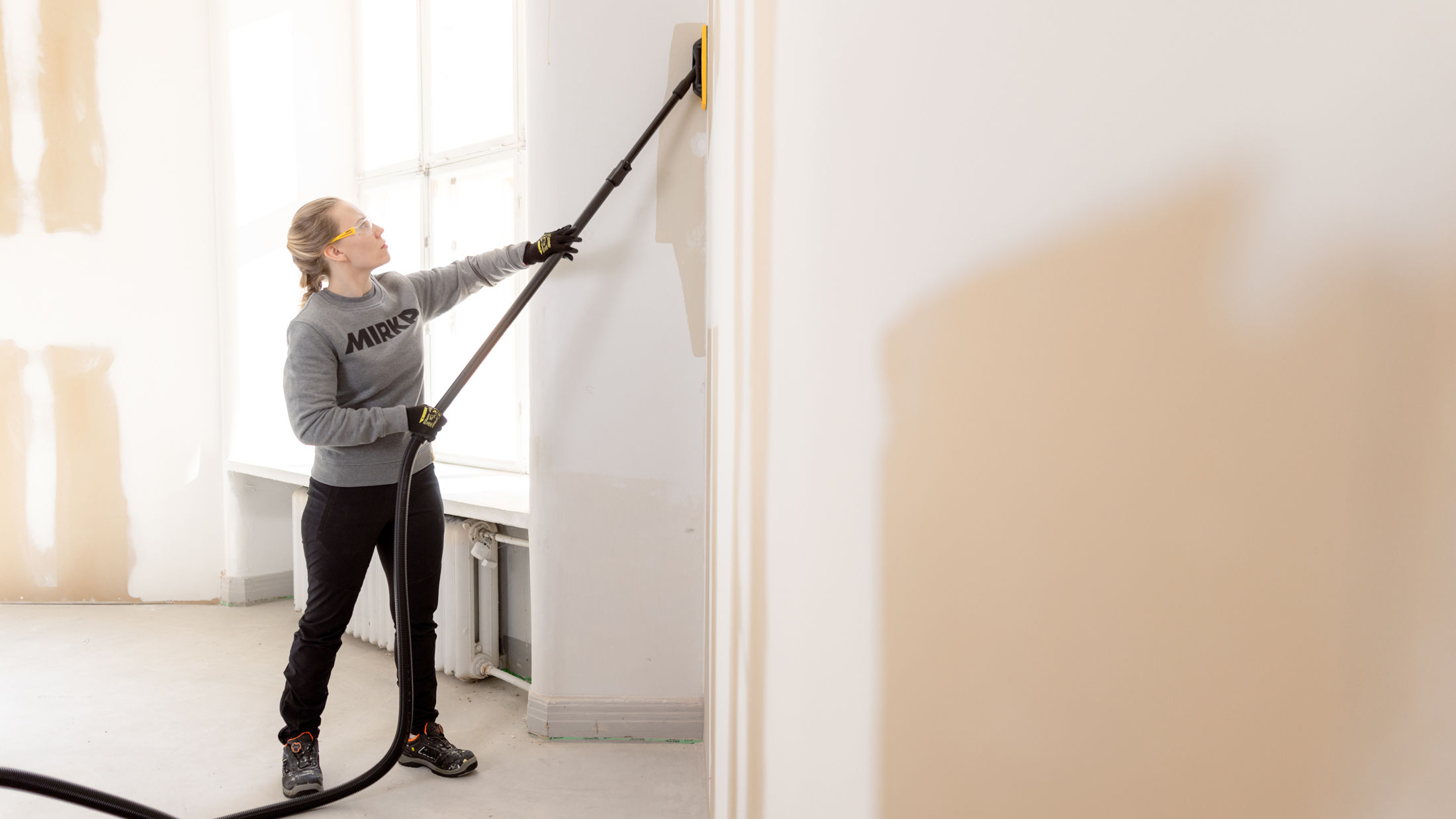 Woman sanding wall using Mirka DecoSander and Abranet Yellow abrasive