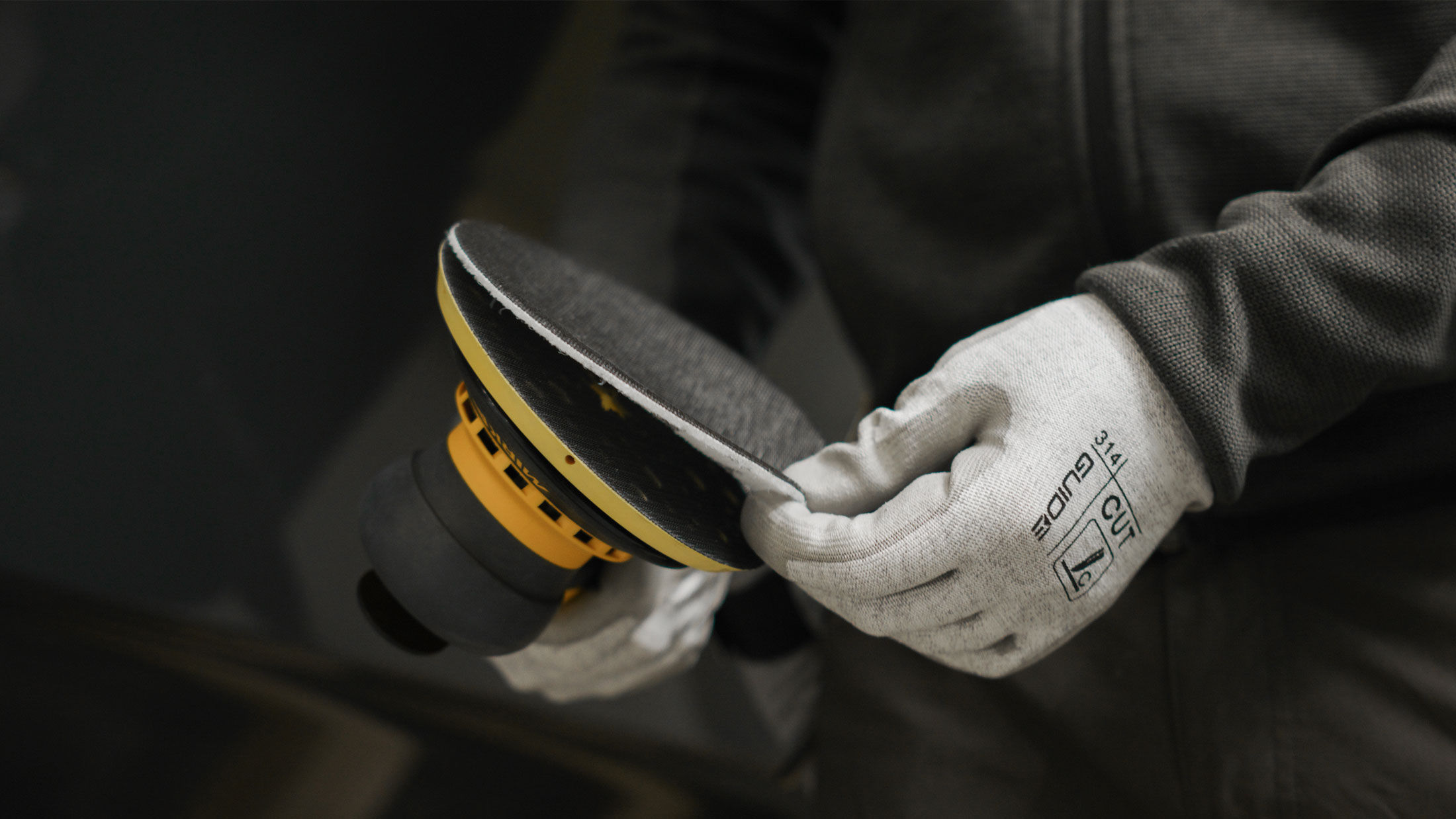 Man with a Mirka DEROS sander adding a Galaxy abrasive.