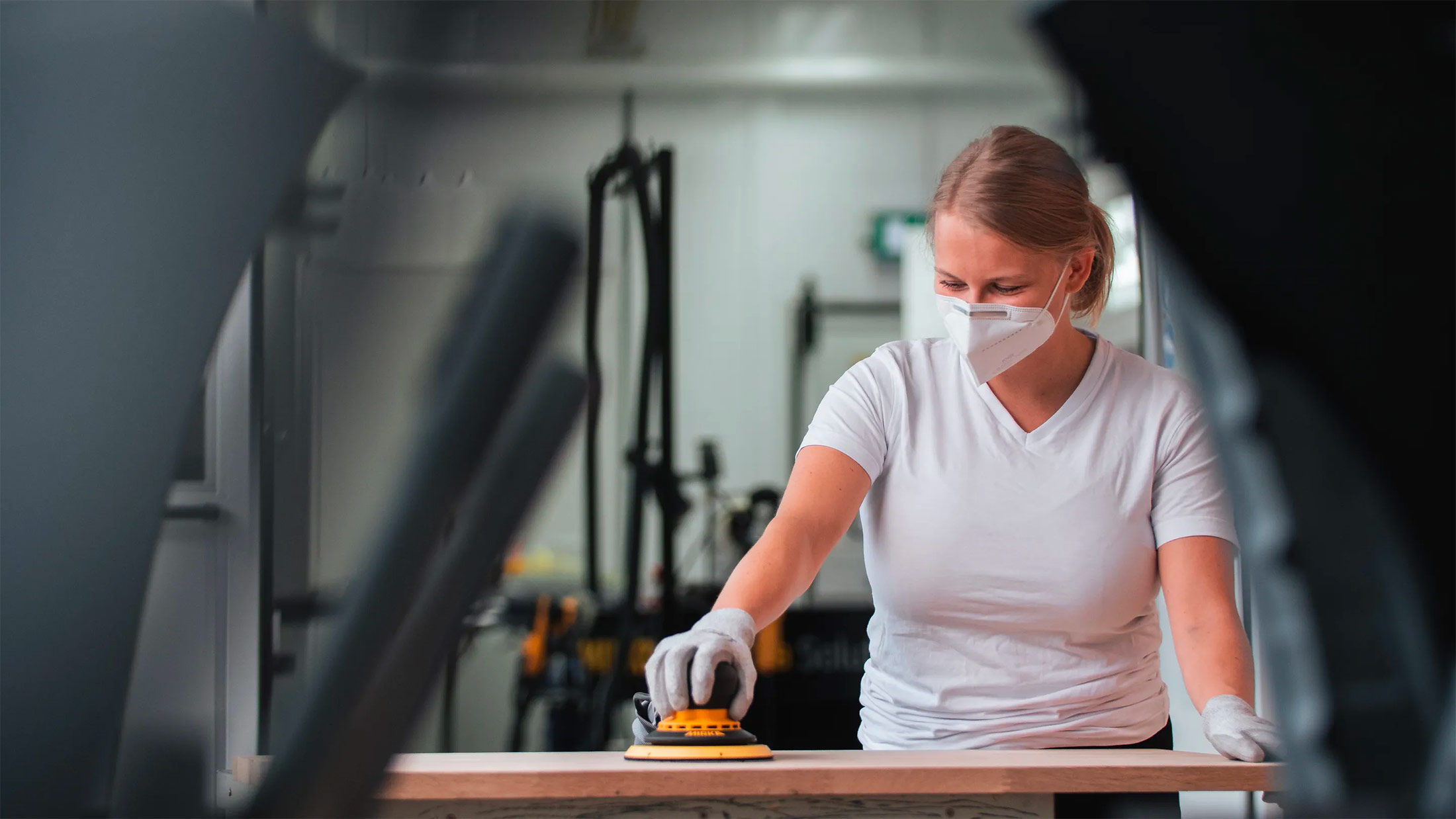 Mujer lijando con un Deros un trozo de madera