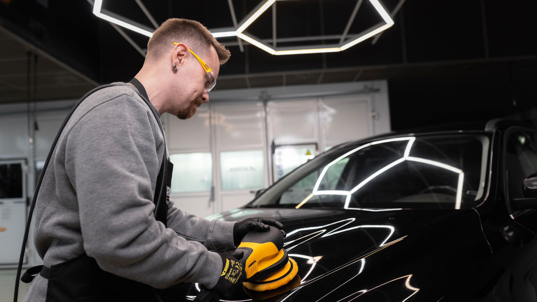 Man polishing the hood of a black car using a POLAROS RP 600 polisher