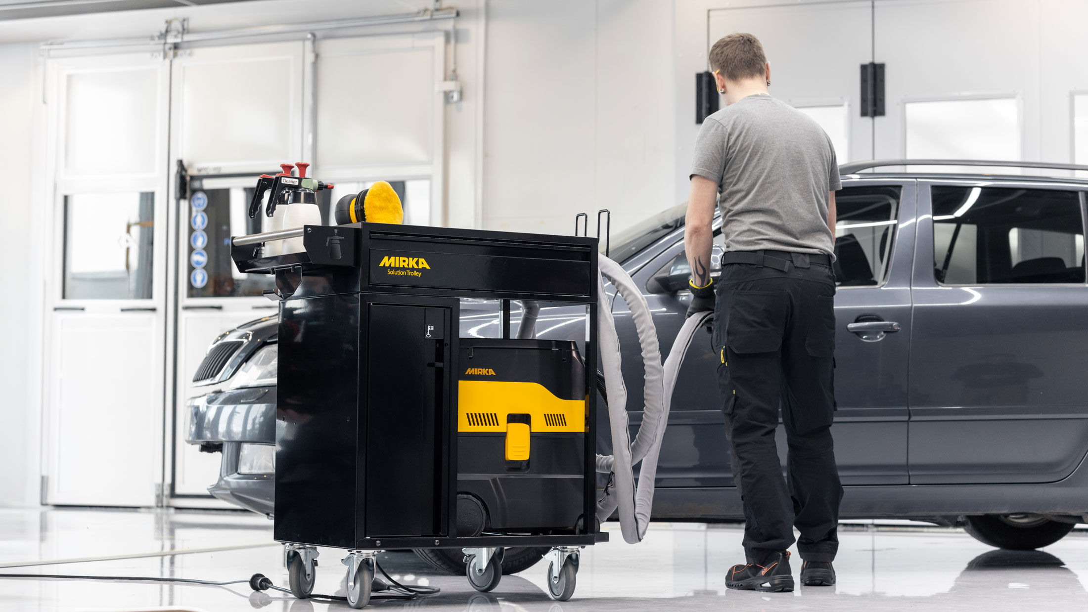 Homem a fazer o acabamento de superfície com o carrinho de apoio de ferramentas Mirka Solution Trolley II