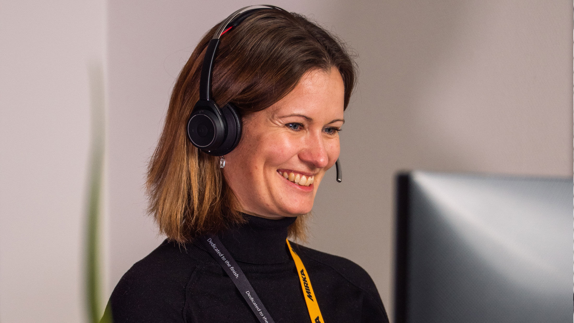 Femme souriante avec un casque devant son ordinateur