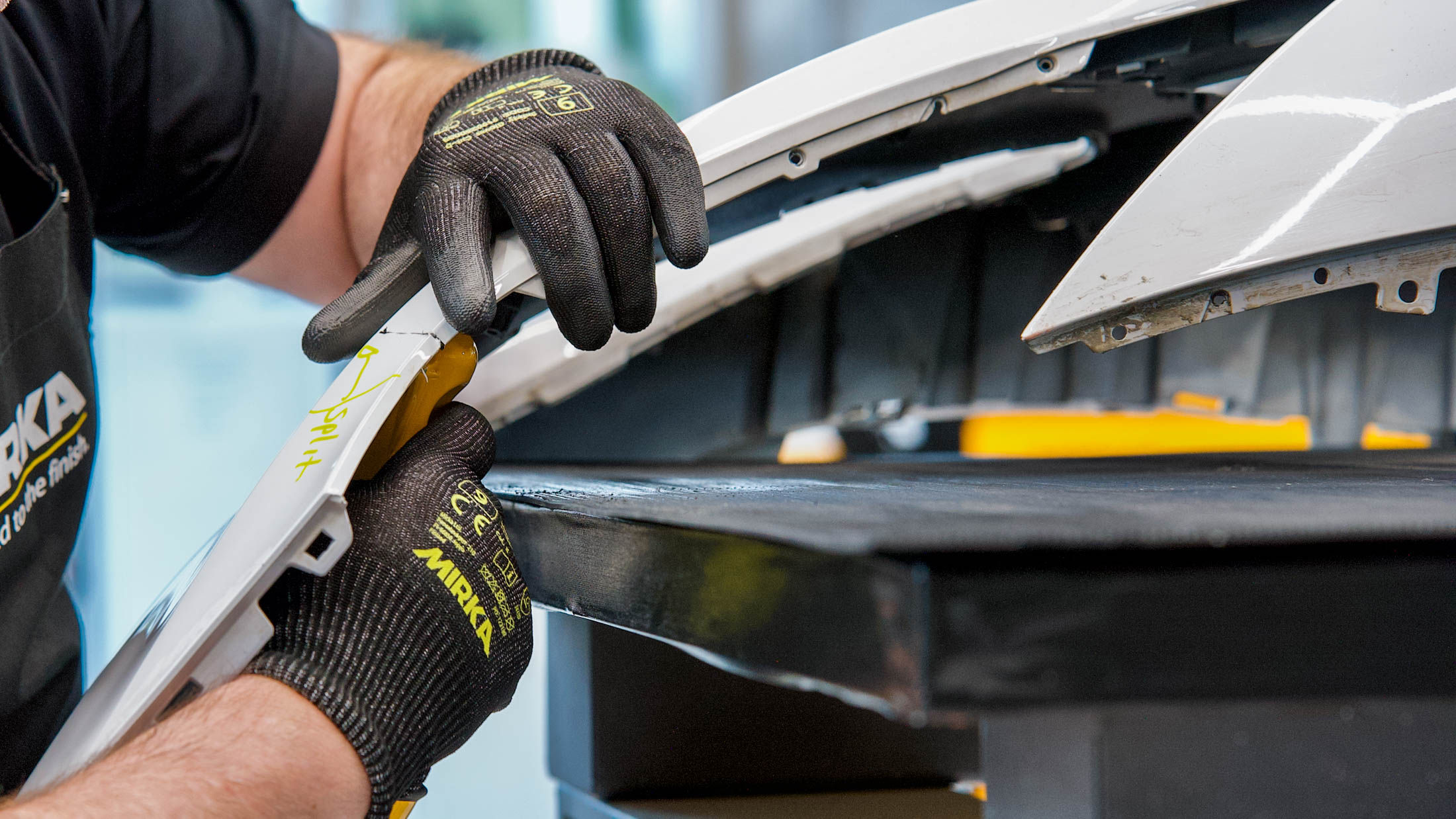 A split on a white bumper being welded and mended with the Mirka Plastic Repair Solution