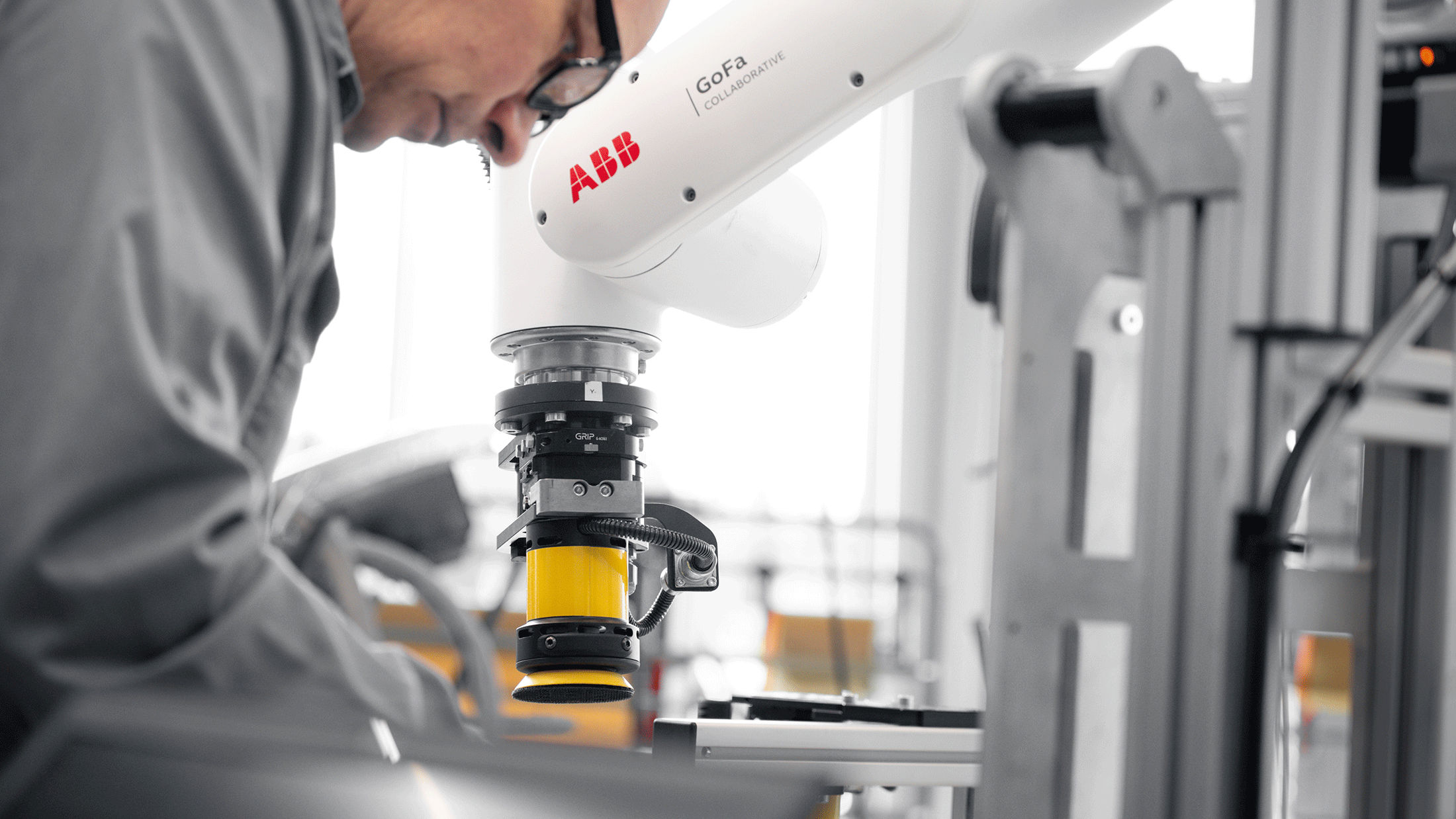 Man programming an industrial ABB robot equipped with a Mirka AIROS sander.