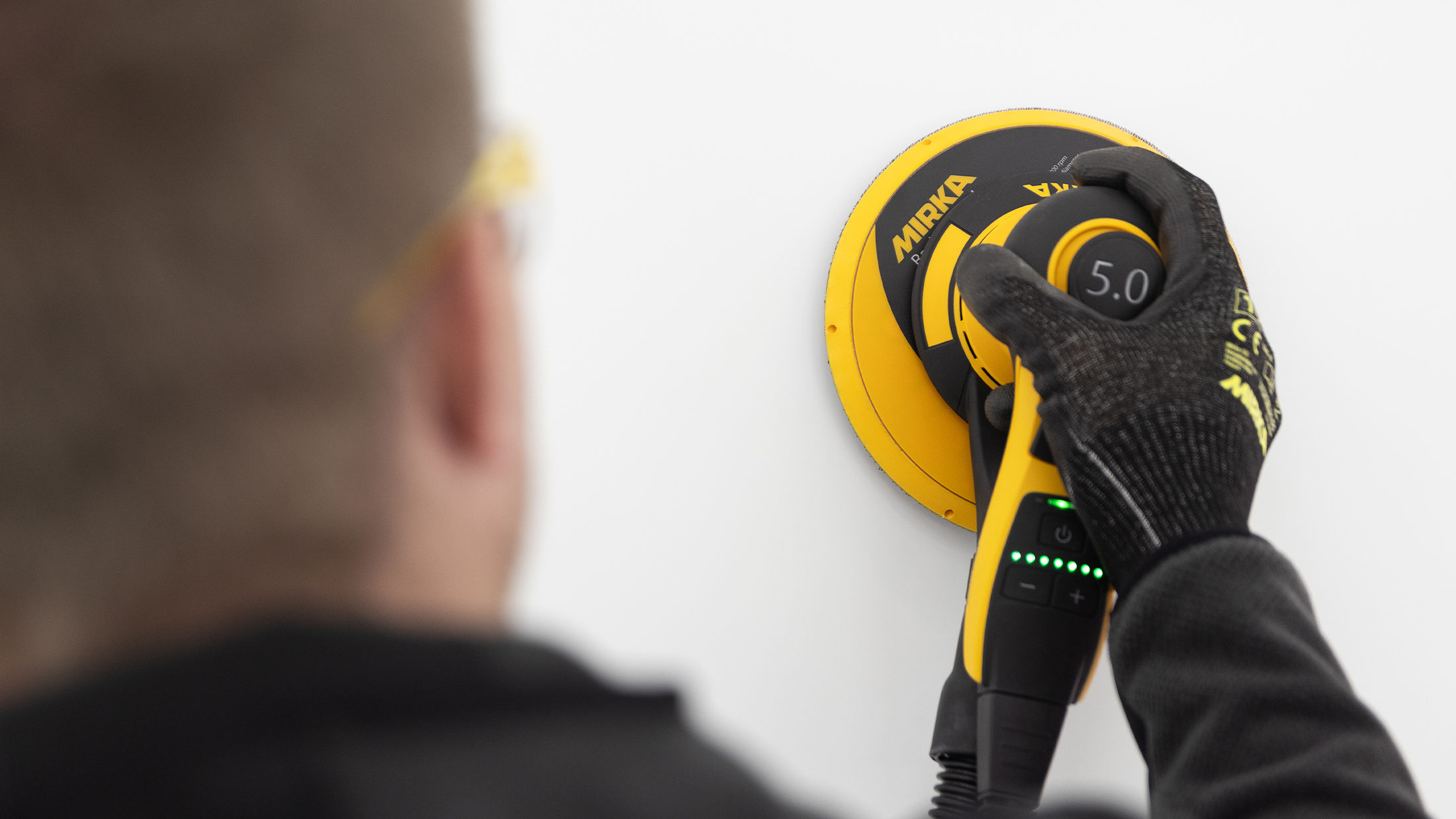Man sanding wall dust-free power tools